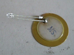 A piezoelectric crystal from a greeting card with LED soldered on.