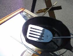 Cast iron pan getting sunlight only from the mirror below in the fresnel lens and mirror solar cooker.