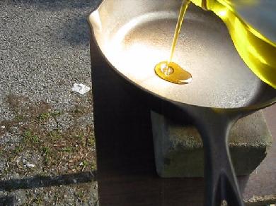 Pouring olive oil in the pan for cooking with my fresnel solar cooker.