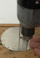 Drilling holes in the displacer's metal disk for sewing on the steel wool.