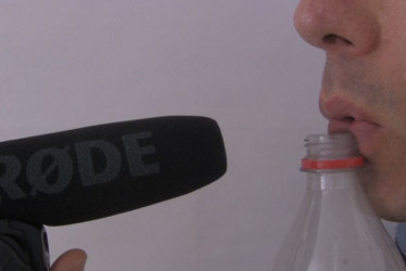 Blowing horizontally across the opening of a bottle to make sound and recording with a microphone.