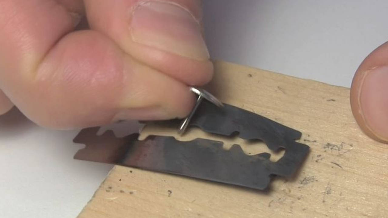 Attaching the blued razor blade to the wood using a thumb tack.