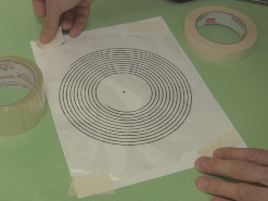 Taping the clear tape down on the template for the spiral primary coil.