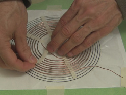 Putting thin pieces of tape on the spiral coil to hold it on.