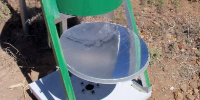 Looking up into Art's hybrid solar oven from to where the parabolic
      dish reflects the sunlight onto a black painted pot.