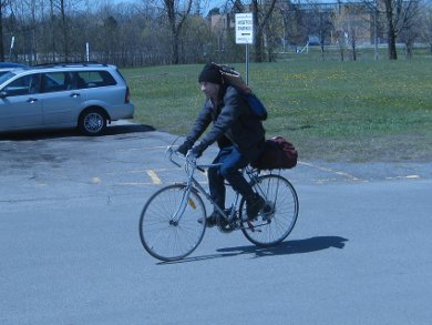 Me arriving at the school to teach solar cooking with folded up 
      Modified CooKit and car sunshade cookers in the backpack on my back.