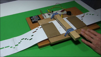 Pulling the paper between the loops and marks for the 555 timer chip music player.