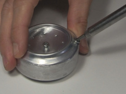 Putting the screws in to plug the holes in the alcohol stove.