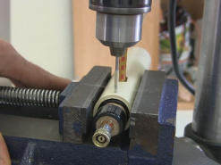 Drilling a hole in the PVC launch tube to lock the dowel in place.