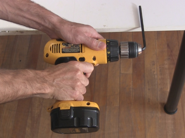 Slamming the allen key against the table to loosen the chuck from the drill.