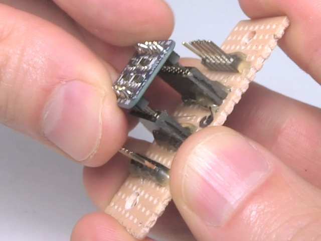 Inserting the soldered board into female pin headers on a perfboard.